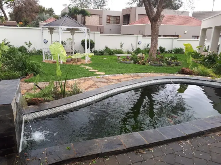 Landscaped koi pond and garden gazebo surrounded by colourful spring planting